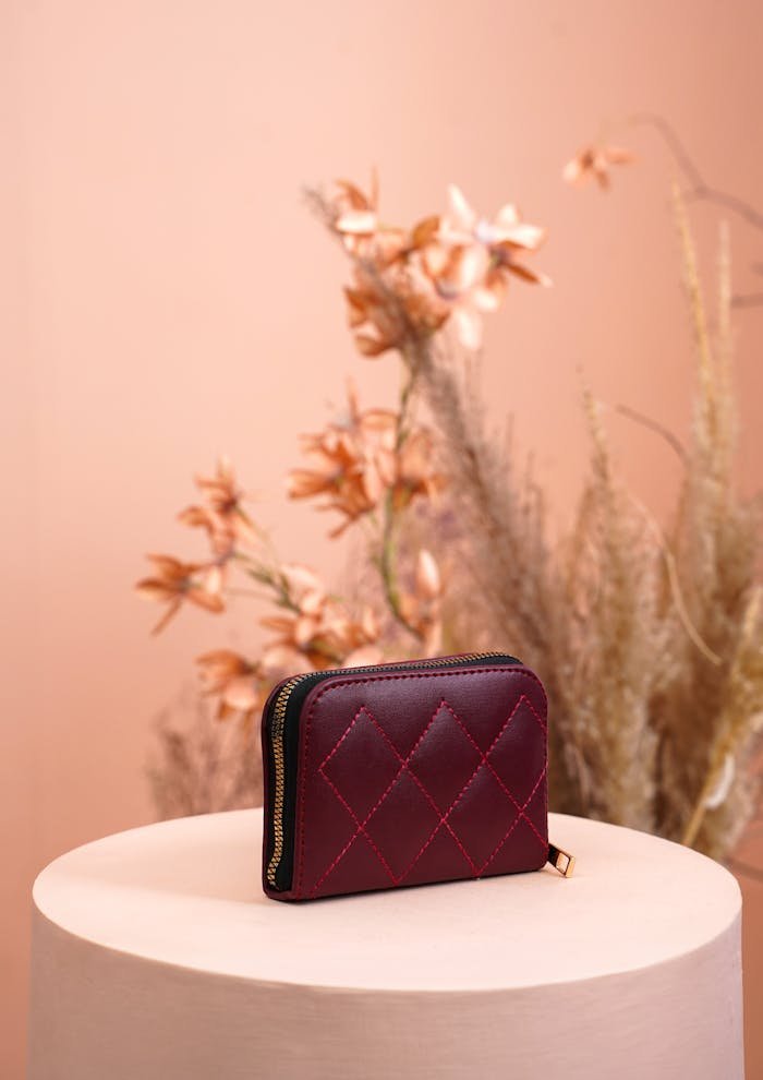 Stylish red wallet displayed against a soft floral backdrop, perfect for fashion photography.