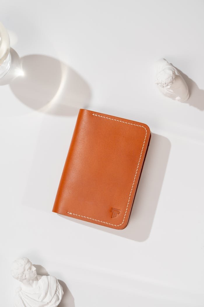 Stylish brown leather wallet on white surface with artistic lighting.